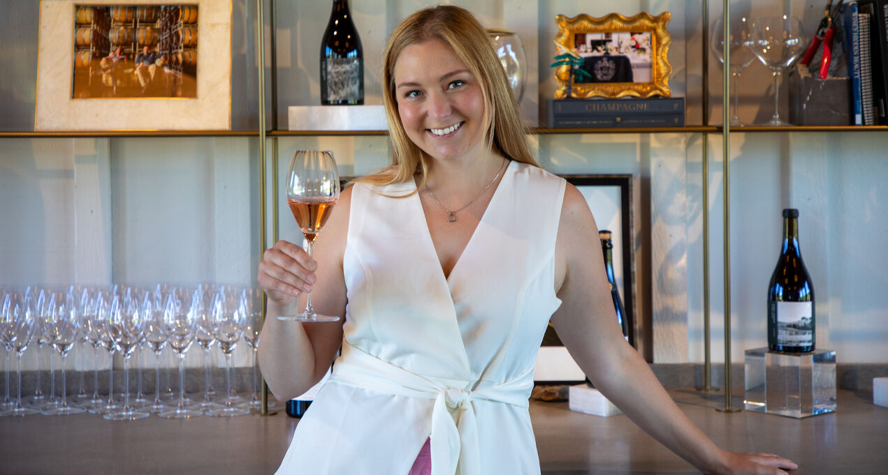 Gran Moraine Concierge, Haley Vachter, holding a glass of Brut Rosé in tasting room.